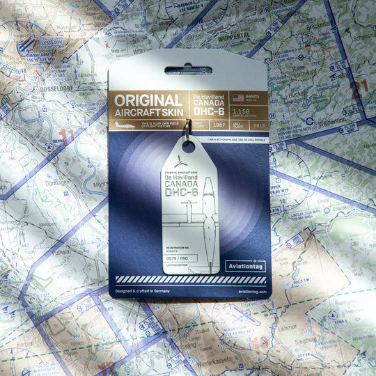 White Twin Otter aircraft tag placed on a world map with miniature airplane, symbolic plane tag made from historic aircraft fuselage