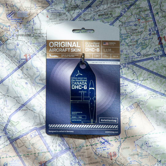 Twin Otter aircraft tag placed on a world map with miniature airplane, symbolic plane tag made from historic aircraft fuselage