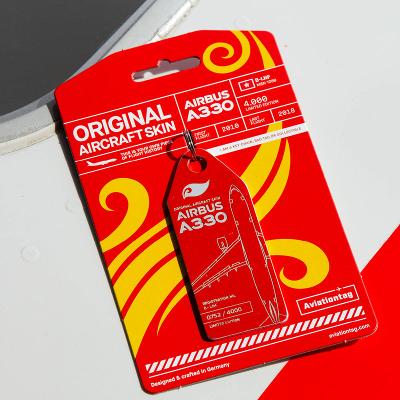 Lifestyle shot: Red Aviationtag keychain on  aircraft panel—plane tag from upcycled aircraft material (Airbus A330-223 B-LNF), aviation memorabilia for collectors.