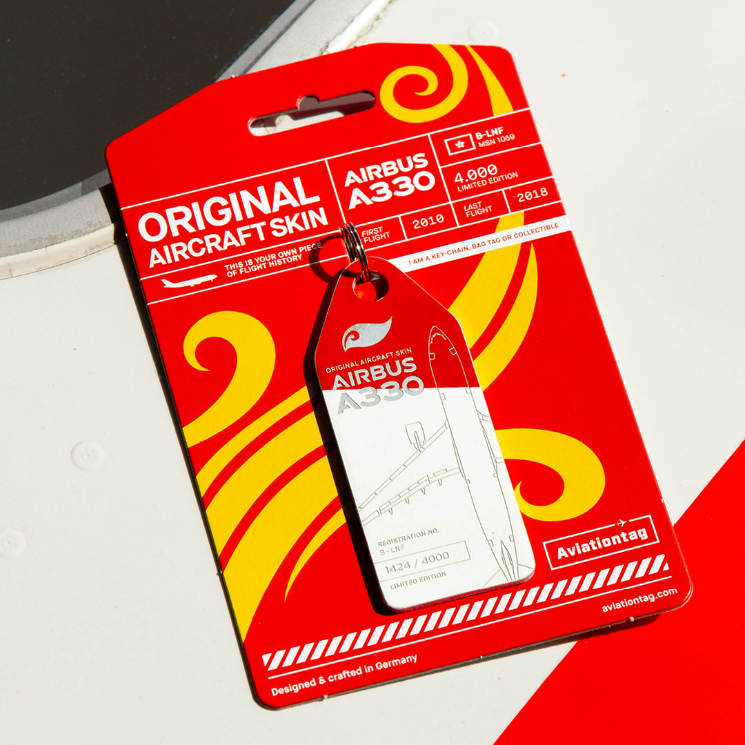 Lifestyle shot: Red/White Aviationtag keychain with backing card on an aircraft panel.