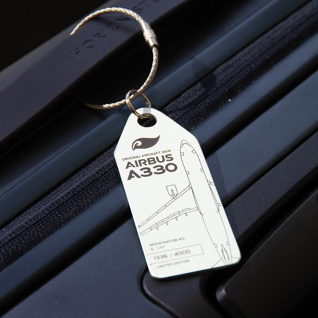 Lifestyle shot: White Aviationtag keychain on luggage—plane tag from upcycled aircraft material (Airbus A330-223 B-LNF), aviation memorabilia for collectors.
