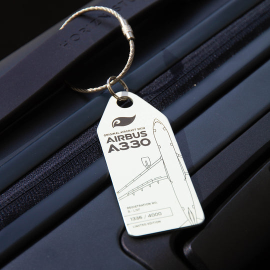 Lifestyle shot: White Aviationtag keychain on luggage—plane tag from upcycled aircraft material (Airbus A330-223 B-LNF), aviation memorabilia for collectors.